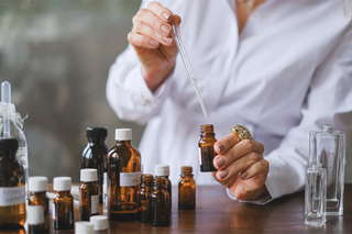 woman in lab coat measuring fragrance oils