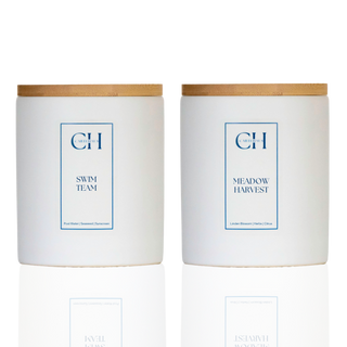 Two candles with wooden lids labeled 'Swim Team' and 'Meadow Harvest' on a white background.
